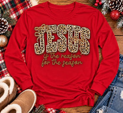 Jesus Is the Reason for the Season Christmas graphic shirt featuring bold leopard print JESUS lettering, decorative gold bows, and gold script. Faith-inspired holiday apparel available in red and black with four style options.