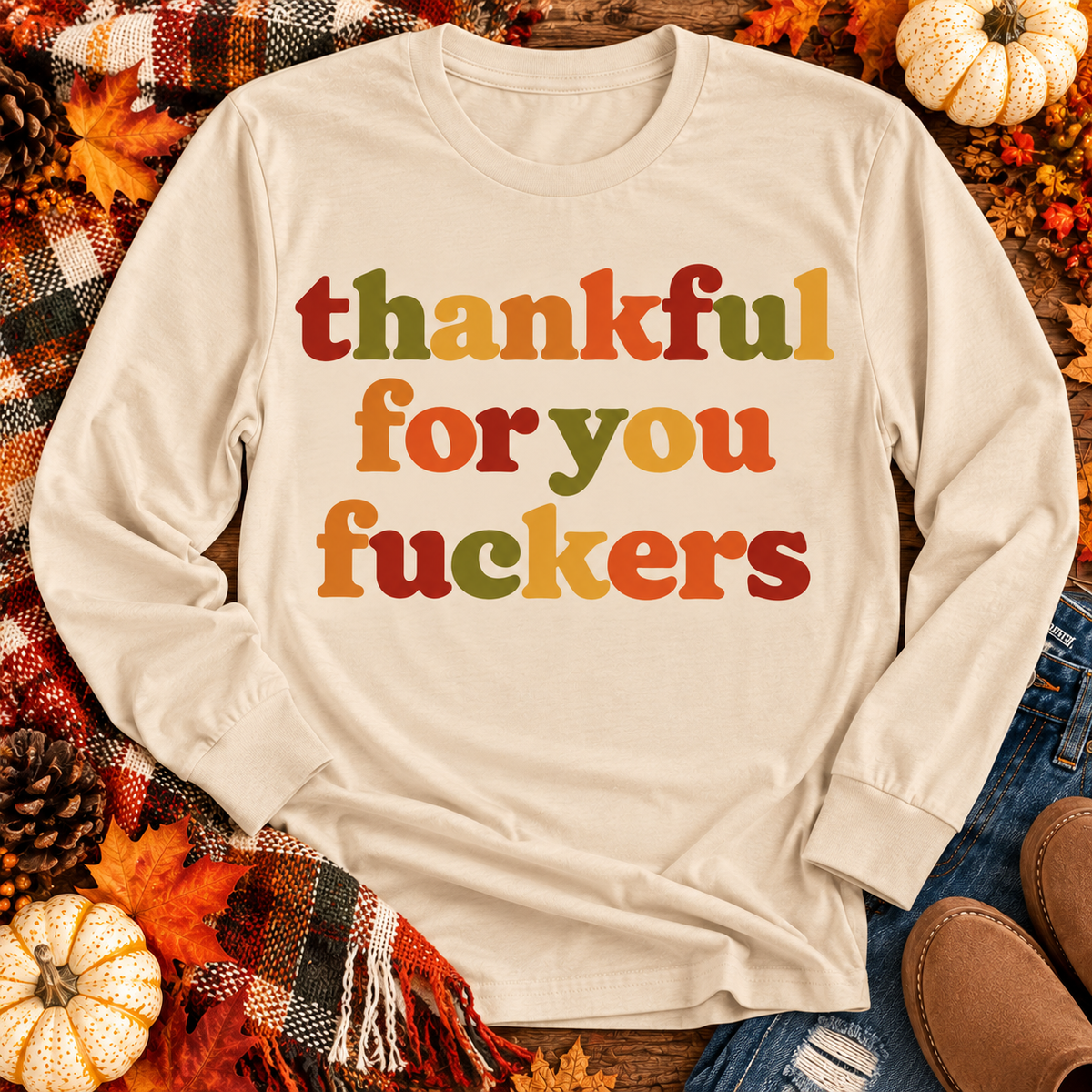 Funny Thankful for You Fuckers Thanksgiving graphic tee featuring bold retro lettering in burnt orange, mustard yellow, olive green, and rust red. Women's fall-inspired short sleeve crewneck shirt available in beige and brown, perfect for Thanksgiving and Friendsgiving.