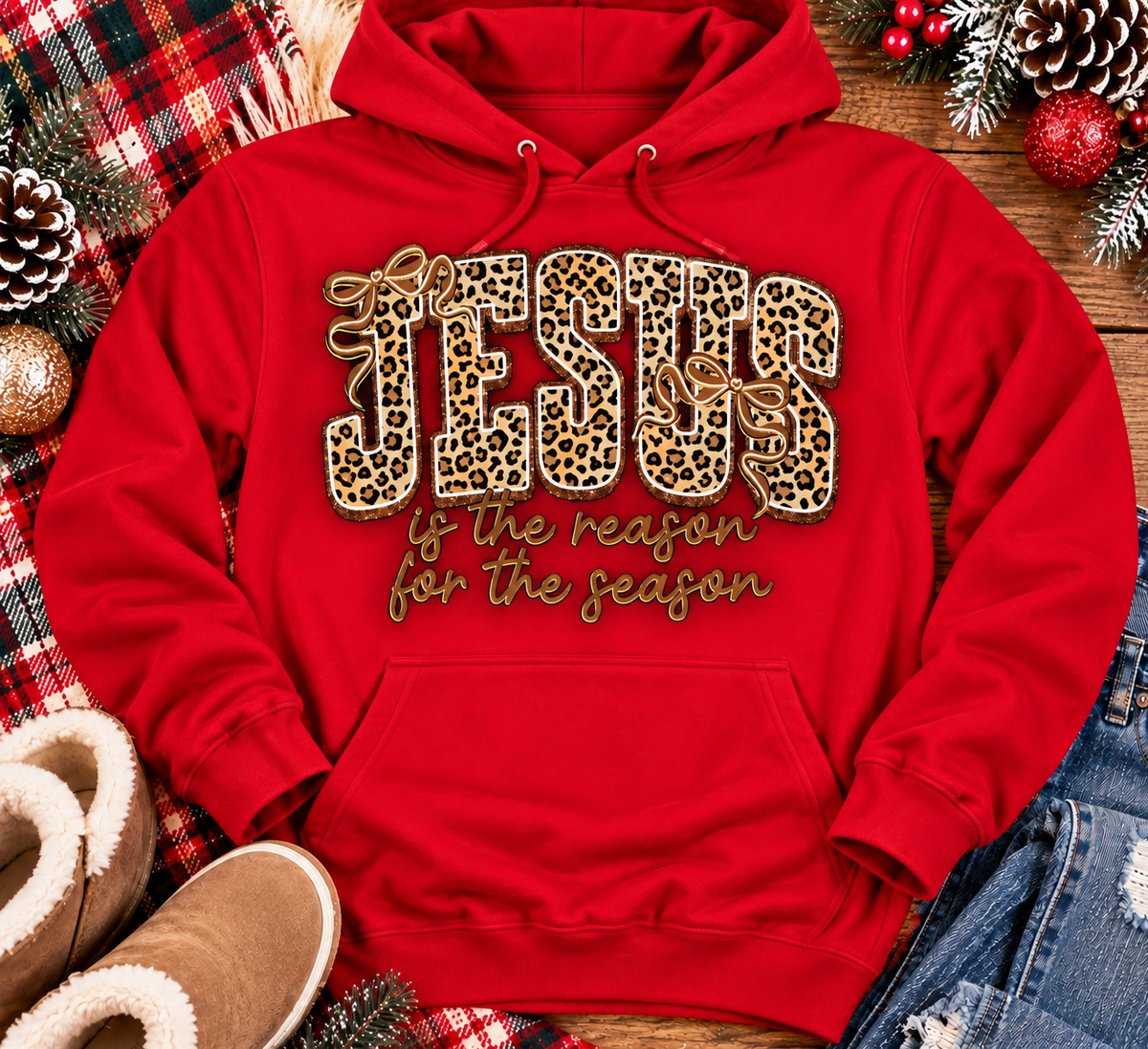 Jesus Is the Reason for the Season Christmas graphic shirt featuring bold leopard print JESUS lettering, decorative gold bows, and gold script. Faith-inspired holiday apparel available in red and black with four style options.