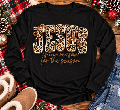 Jesus Is the Reason for the Season Christmas graphic shirt featuring bold leopard print JESUS lettering, decorative gold bows, and gold script. Faith-inspired holiday apparel available in red and black with four style options.