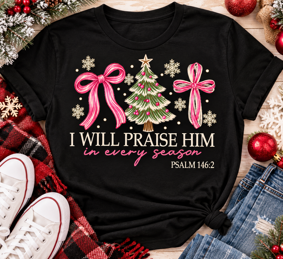 Christian Christmas shirt featuring I Will Praise Him in Every Season Psalm 146:2 graphic with pink bows, decorated Christmas tree, and cream snowflakes.