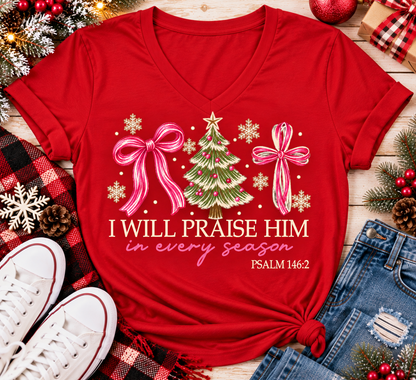 Christian Christmas shirt featuring I Will Praise Him in Every Season Psalm 146:2 graphic with pink bows, decorated Christmas tree, and cream snowflakes.