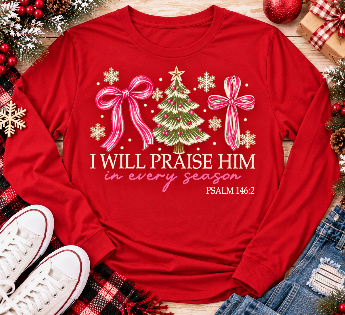 Christian Christmas shirt featuring I Will Praise Him in Every Season Psalm 146:2 graphic with pink bows, decorated Christmas tree, and cream snowflakes.