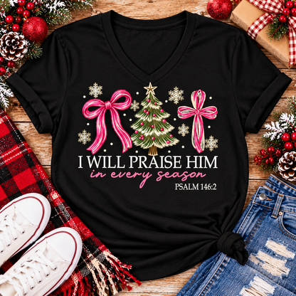Christian Christmas shirt featuring I Will Praise Him in Every Season Psalm 146:2 graphic with pink bows, decorated Christmas tree, and cream snowflakes.